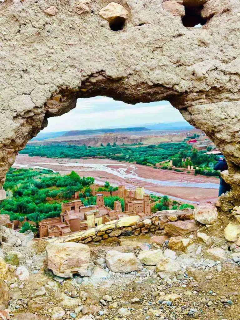 View of the Ait Ben Haddou kasbah and river valley framed through a stone wall opening