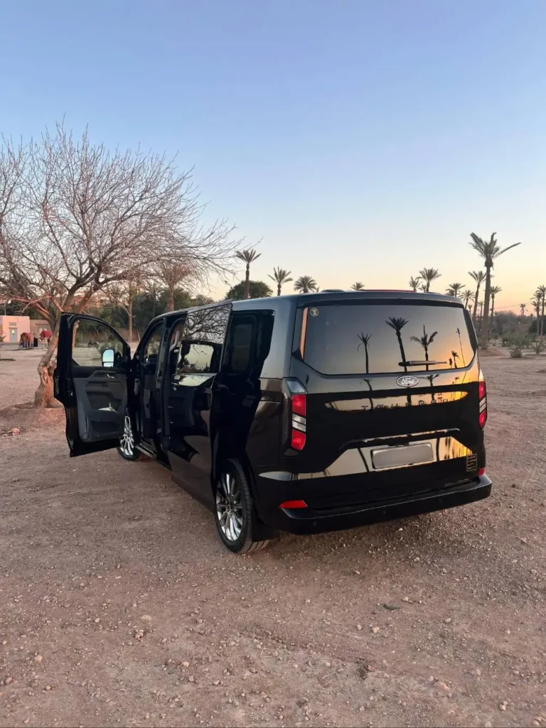 Black Ford Tourneo van with open doors parked in the Marrakech palm grove at sunset